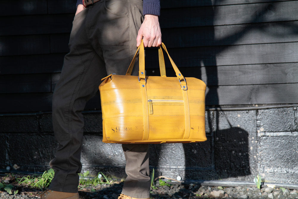 Man holding yellow travel bag