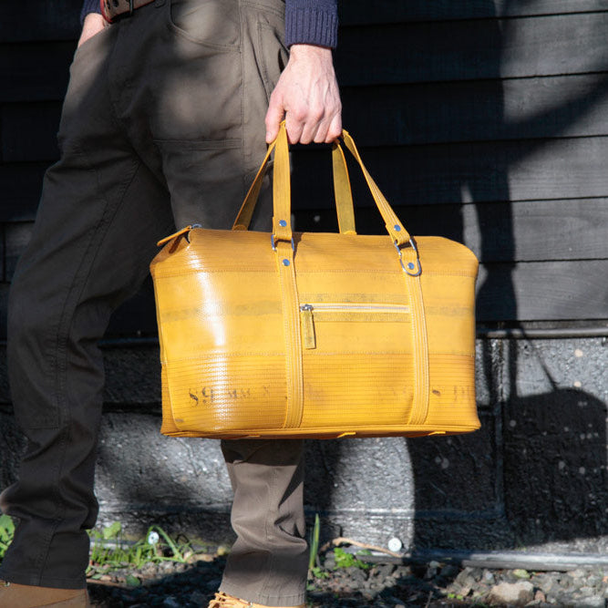 Man holding yellow travel bag