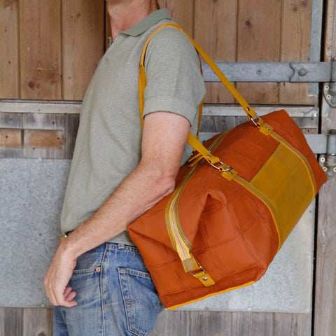 The Elvis & Kresse Weekend Bag, available in cider camel upcycled leather and yellow recycled fire-hose
